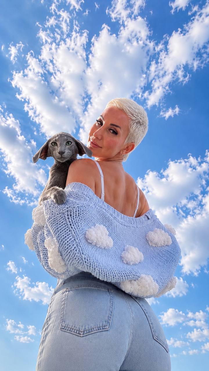 Eastern Grace Cattery owner outdoors holding a gray kitten with wide, downward-angled ears.